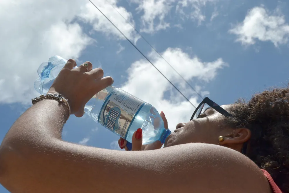 Pessoa se hidratando no calor de Cuiabá